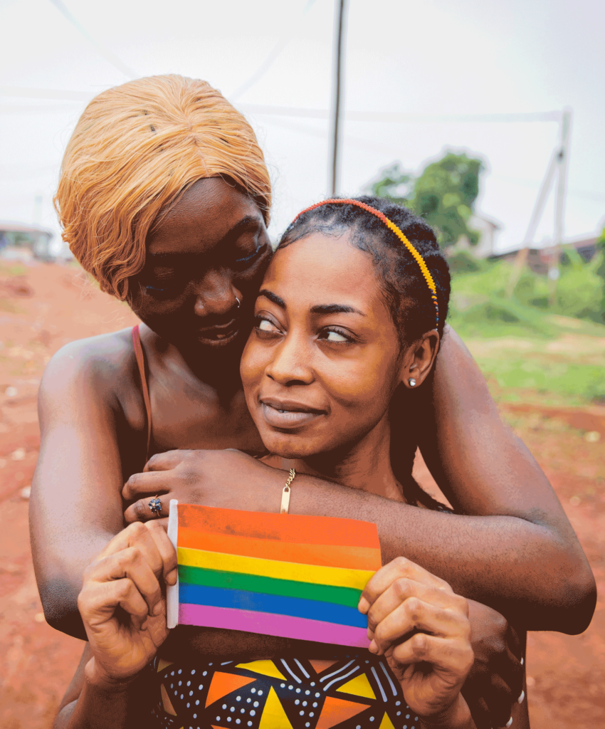 African lesbian women couple hugging, girlfriend holds a rainbow flag, homosexual love.